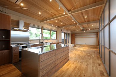 他の地域にあるモダンスタイルのおしゃれなキッチン (ステンレスカウンター、木材のキッチンパネル、板張り天井) の写真