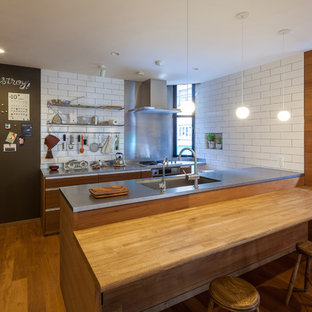 Foto di una cucina minimal con lavello a vasca singola, top in acciaio inossidabile, paraspruzzi bianco, pavimento in legno massello medio, nessun'anta, paraspruzzi con piastrelle diamantate, penisola e ante in legno scuro