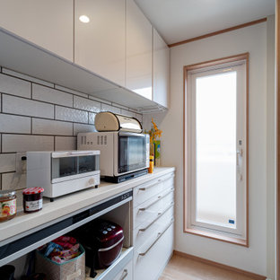 Cette photo montre une cuisine ouverte linéaire avec un évier 1 bac, un placard à porte plane, des portes de placard blanches, une crédence blanche, un sol en contreplaqué, un sol marron, un plan de travail beige et un plafond en papier peint.