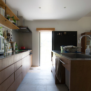 Mittelgroße, Einzeilige Shabby-Look Wohnküche mit Unterbauwaschbecken, Edelstahl-Arbeitsplatte, Betonboden, Kücheninsel, grauem Boden und flächenbündigen Schrankfronten in Sonstige
