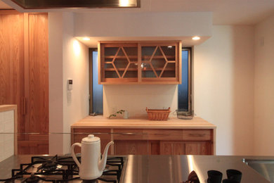 Diseño de cocina lineal pequeña abierta con fregadero integrado, encimera de acero inoxidable, electrodomésticos de acero inoxidable y una isla