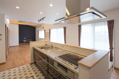 Foto di una cucina contemporanea di medie dimensioni con lavello integrato, ante lisce, top in acciaio inossidabile, paraspruzzi bianco, elettrodomestici neri, pavimento in vinile e pavimento bianco