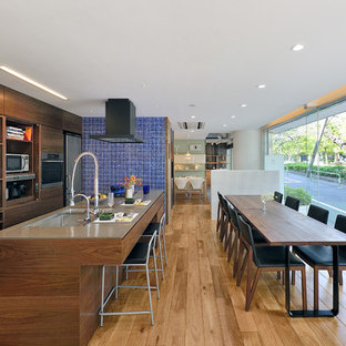 Photo of a contemporary single-wall eat-in kitchen in Tokyo with a double-bowl sink, flat-panel cabinets, medium wood cabinets, glass benchtops, stainless steel appliances, light hardwood floors and with island.