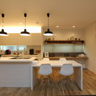 Country galley eat-in kitchen in Tokyo with an undermount sink, flat-panel cabinets, medium wood cabinets, onyx benchtops, stainless steel appliances, light hardwood floors, multiple islands and beige floor.