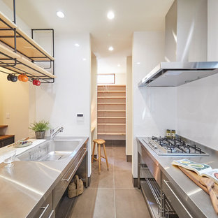 Industrial kitchen in Tokyo Suburbs with an integrated sink, flat-panel cabinets, stainless steel cabinets, stainless steel benchtops, a peninsula, grey floor and white benchtop.