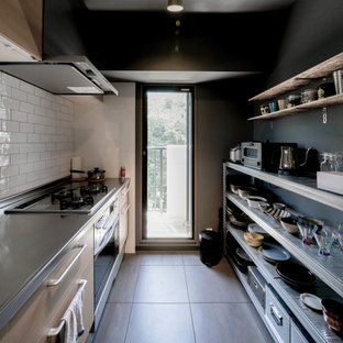 Idée de décoration pour une cuisine linéaire minimaliste fermée avec un évier intégré, un placard à porte affleurante, des portes de placard en bois clair, un plan de travail en inox, une crédence blanche, une crédence en mosaïque, un électroménager en acier inoxydable, un sol en vinyl, un sol gris et un plafond en papier peint.