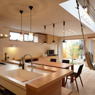 Inspiration för asiatiska linjära kök med öppen planlösning, med rostfria vitvaror, en integrerad diskho, släta luckor, vita skåp, ljust trägolv och en halv köksö