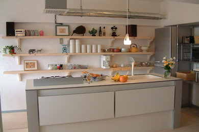 Diseño de cocina contemporánea pequeña abierta con armarios con paneles lisos, electrodomésticos blancos, suelo de madera clara y una isla