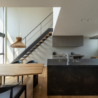 Esempio di una cucina scandinava di medie dimensioni con lavello sottopiano, ante a filo, ante grigie, top in laminato, paraspruzzi bianco, elettrodomestici in acciaio inossidabile, pavimento in legno massello medio, penisola, pavimento marrone, top marrone e soffitto in carta da parati