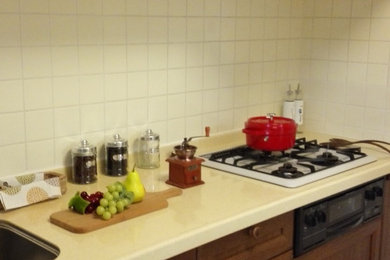 Réalisation d'une petite cuisine linéaire nordique en bois foncé fermée avec un évier encastré, un placard à porte affleurante, un plan de travail en surface solide, une crédence blanche, une crédence en carreau de porcelaine, un électroménager noir, un sol en vinyl, aucun îlot et un sol blanc.