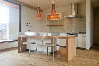 Photo of a medium sized scandi galley open plan kitchen in Other with an integrated sink, flat-panel cabinets, white cabinets, composite countertops, stainless steel appliances, plywood flooring and an island.