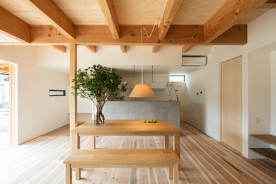Foto di una sala da pranzo aperta verso la cucina etnica con pareti bianche, parquet chiaro e pavimento beige