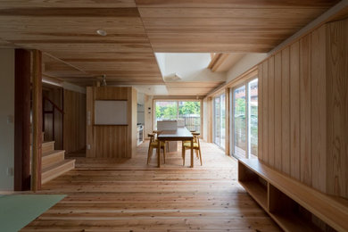 Diseño de comedor asiático grande abierto con paredes beige, suelo de madera en tonos medios y suelo beige