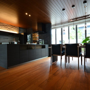 Modern inredning av en matplats med öppen planlösning, med bruna väggar, plywoodgolv och rosa golv