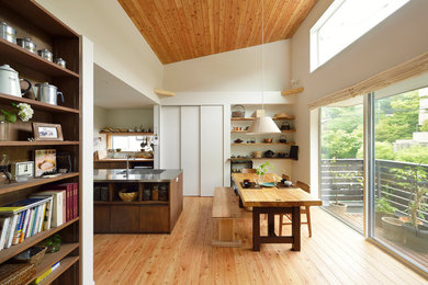 Réalisation d'une salle à manger ouverte sur la cuisine asiatique avec un mur blanc, un sol en bois brun et un sol marron.