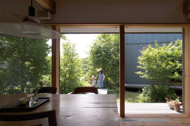 Imagen de comedor de estilo zen de tamaño medio con paredes blancas, suelo de madera en tonos medios, estufa de leña, marco de chimenea de metal y suelo marrón