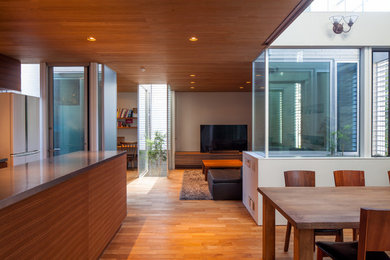 Aménagement d'une salle à manger ouverte sur le salon rétro avec un mur blanc, un sol en bois brun et un sol marron.