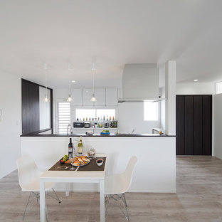 Esempio di una sala da pranzo aperta verso il soggiorno minimalista con pareti bianche, pavimento in compensato, nessun camino e pavimento bianco