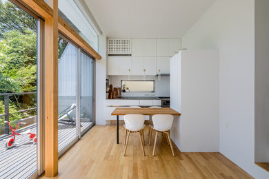 Imagen de comedor blanco minimalista pequeño abierto sin chimenea con suelo de madera en tonos medios