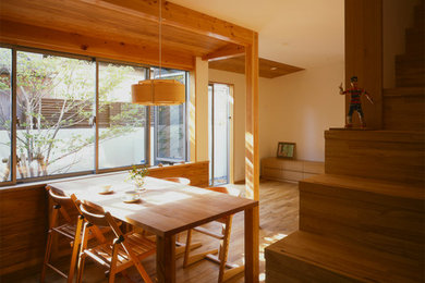 Aménagement d'une salle à manger ouverte sur le salon asiatique de taille moyenne avec un mur blanc et un sol en bois brun.