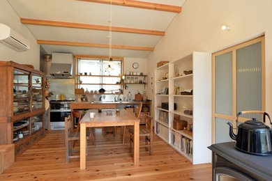 Imagen de comedor campestre de tamaño medio abierto con paredes blancas, suelo de madera en tonos medios, estufa de leña y marco de chimenea de baldosas y/o azulejos
