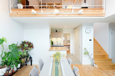Immagine di una sala da pranzo aperta verso il soggiorno nordica con pareti bianche e parquet chiaro