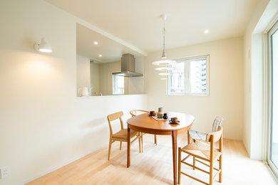 Foto di una sala da pranzo nordica con pareti bianche, parquet chiaro e pavimento beige