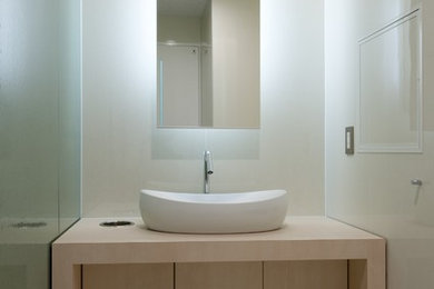 他の地域にあるモダンスタイルのおしゃれなトイレ・洗面所 (淡色木目調キャビネット、大理石の床、ベッセル式洗面器、白い床) の写真
