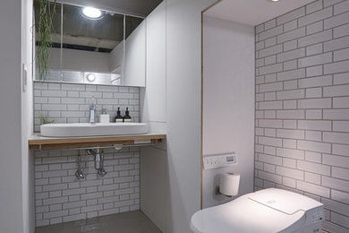 Immagine di un bagno di servizio industriale con piastrelle bianche, pareti bianche, pavimento in cemento, lavabo a bacinella, top in legno, pavimento grigio e top marrone