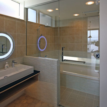 ガラス張りの浴室は洗面と同じ総タイル張り