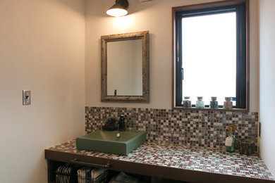 他の地域にあるアジアンスタイルのおしゃれなトイレ・洗面所 (オープンシェルフ、ヴィンテージ仕上げキャビネット、白い壁、ベッセル式洗面器、タイルの洗面台、茶色い床、マルチカラーの洗面カウンター) の写真