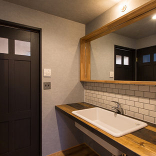 Inspiration pour un WC et toilettes urbain de taille moyenne avec un placard sans porte, des portes de placard grises, un bidet, un carrelage blanc, des carreaux de céramique, un mur gris, un sol en bois clair, un lavabo posé, un plan de toilette en bois, un sol beige, un plan de toilette marron, meuble-lavabo encastré, un plafond en papier peint et du papier peint.
