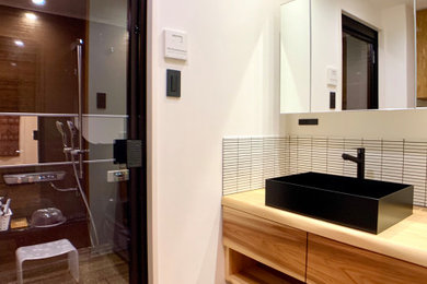 Small modern cloakroom in Other with freestanding cabinets, medium wood cabinets, white tiles, porcelain tiles, white walls, wood-effect flooring, a vessel sink, wooden worktops, brown floors, a built in vanity unit, a wallpapered ceiling and wallpapered walls.