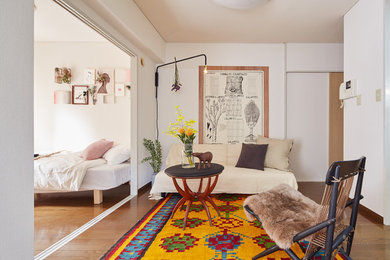 Imagen de sala de estar abierta bohemia pequeña sin chimenea con paredes blancas y suelo de madera en tonos medios