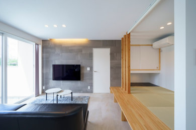 Imagen de sala de estar abierta minimalista de tamaño medio con paredes grises, suelo vinílico, televisor colgado en la pared y suelo beige