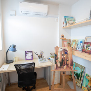 Bild på ett litet hemmastudio, med vita väggar, målat trägolv, ett fristående skrivbord och beiget golv