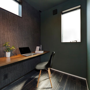 Arbeitszimmer mit Arbeitsplatz, brauner Wandfarbe, dunklem Holzboden, Einbau-Schreibtisch, braunem Boden, Tapetendecke und Tapetenwänden in Sonstige