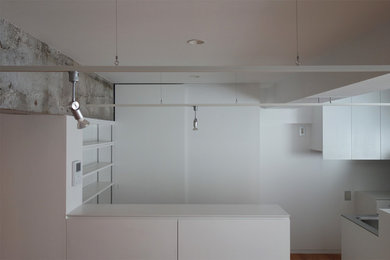 Modern study in Tokyo Suburbs with white walls, light hardwood flooring and a built-in desk.