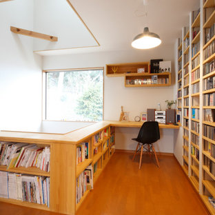 Modernes Arbeitszimmer mit weißer Wandfarbe, braunem Holzboden, Einbau-Schreibtisch und braunem Boden in Sonstige