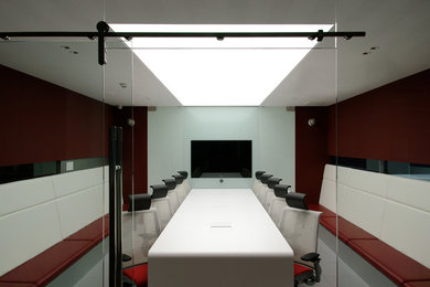 Modelo de estudio minimalista con paredes rojas, suelo vinílico y escritorio independiente