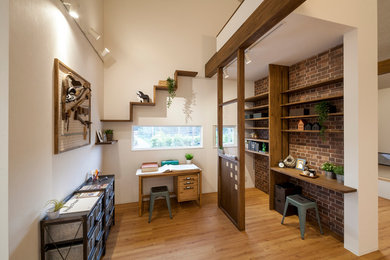 Industrial Arbeitszimmer mit bunten Wänden, braunem Holzboden, freistehendem Schreibtisch und braunem Boden in Yokohama