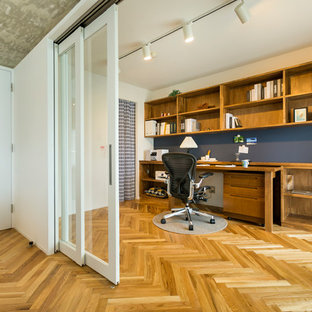 Foto di uno studio scandinavo con pareti bianche, pavimento in legno massello medio, scrivania incassata e pavimento marrone