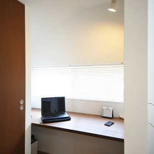 Idéer för att renovera ett litet funkis arbetsrum, med ett bibliotek, vita väggar, plywoodgolv, ett inbyggt skrivbord och brunt golv