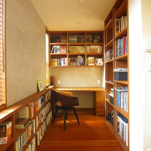 Retro Arbeitszimmer ohne Kamin mit Arbeitsplatz, beiger Wandfarbe, braunem Holzboden, Einbau-Schreibtisch und braunem Boden in Sonstige