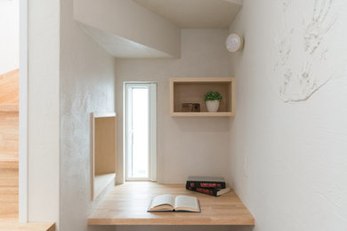 Diseño de despacho escandinavo pequeño con paredes blancas, suelo de madera en tonos medios, escritorio empotrado y suelo marrón