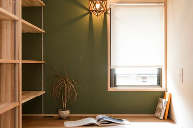 他の地域にあるインダストリアルスタイルのおしゃれな書斎 (緑の壁、無垢フローリング、造り付け机、茶色い床) の写真