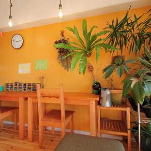 Immagine di uno studio tropicale con pareti arancioni, pavimento in legno massello medio, scrivania autoportante e pavimento marrone