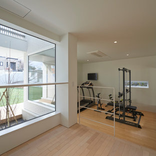 Foto di una sala pesi nordica con pareti bianche e pavimento in legno massello medio