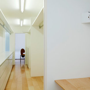 Modern inredning av en vita parallell vitt liten tvättstuga med garderob, med vita väggar, målat trägolv, beiget golv, en undermonterad diskho, släta luckor, vita skåp och laminatbänkskiva