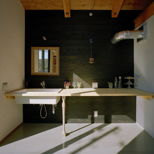 Inspiration för industriella linjära beige tvättstugor, med en nedsänkt diskho, träbänkskiva, svarta väggar, öppna hyllor och grått golv